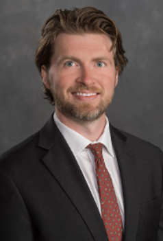 Headshot of Jeffrey Ryan Brown in a black suit and red tie.